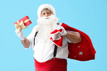 Santa Claus with bag and Christmas gift on blue background