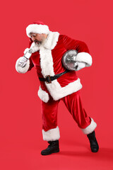 Cool Santa Claus with disco ball and microphone singing Christmas song on red background