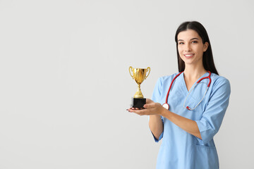 Female doctor with gold cup on light background