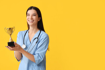 Female doctor with gold cup on yellow background