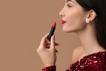 Beautiful young woman with red lipstick on brown background