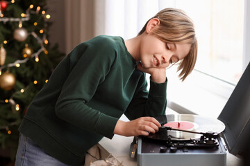 Cute little boy listening music through record player at home  on Christmas eve