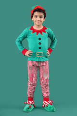 Cute little boy in elf costume on green background