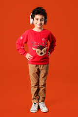 Fototapeta premium Cute little boy in headphones orange background