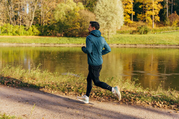 Obraz na płótnie Canvas Man training in the afternoon in the autumn cold season. Athlete warm clothes for fitness. Jogging, warm-up every day, healthy lifestyle.