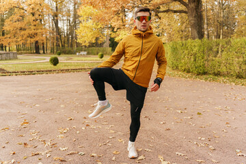 An athlete does leg exercises every day in winter. Warm-up of leg muscles fitness preparation for training running in autumn in the cold in the park.  Active training in winter in the park.