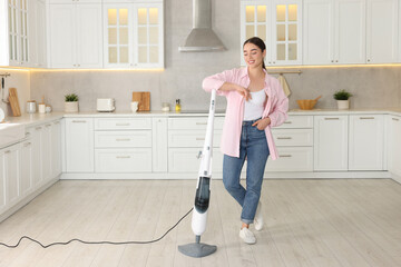 Happy woman with steam mop in kitchen at home