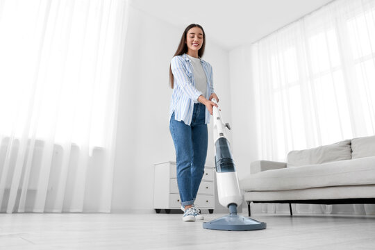 Woman cleaning floor with steam mop at home, low angle view
