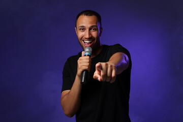 Handsome man with microphone singing on blue background