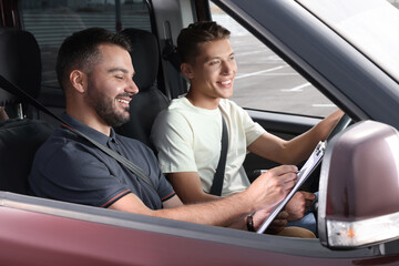 Driving school. Happy student passing driving test with examiner in car at parking lot