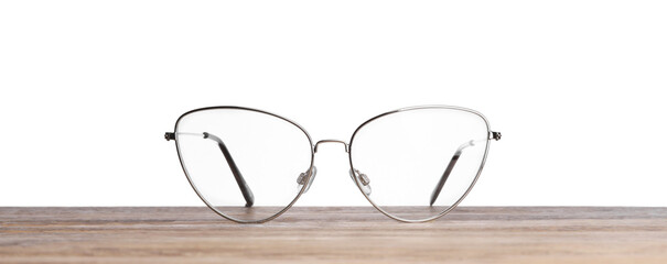 Stylish glasses with metal frame on wooden table against white background