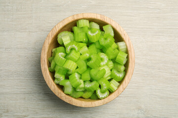 Fresh cut celery stalks in bowl on wooden table, top view