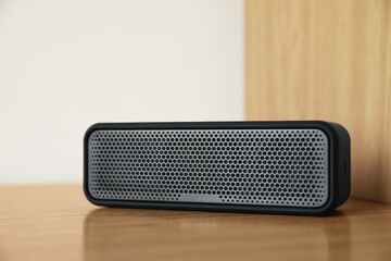 One portable bluetooth speaker on wooden table. Audio equipment