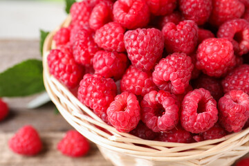 Tasty ripe raspberries in wicker basket, closeup