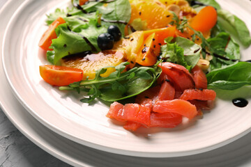 Delicious salad with salmon on white plate, closeup