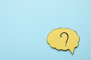 Paper speech bubble with question mark on light blue background, top view. Space for text