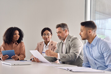 Senior company manager consulting managing busy team work at corporate meeting. Diverse international professional executive team people in office having discussion in board room.