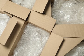 Many open cardboard boxes with bubble wrap as background, top view
