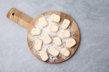 Making lazy dumplings. Board with cut dough and flour on grey table, top view