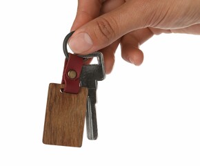 Woman holding key with wooden keychain on white background, closeup