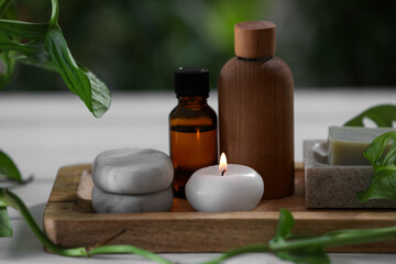 Beautiful composition with different spa products and green leaves on white table, closeup
