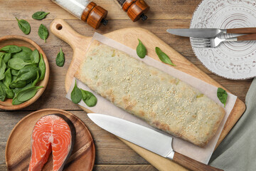 Delicious strudel with salmon and spinach on wooden table, flat lay