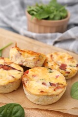 Delicious egg muffins with cheese and bacon on wooden board, closeup. Space for text