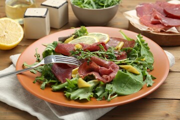 Delicious bresaola salad served on wooden table, closeup
