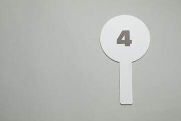 Auction paddle with number 4 on light grey background, top view. Space for text