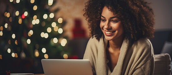 A happy Black woman with a cup watching her laptop at home during Christmas