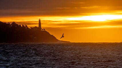 Lever de soleil sur la mer à Nice sur la Côte d'Azur avec des lueurs dorées sur le phare du Cap...