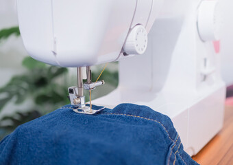 Close up sewing machine sew seam of blue denim jean.