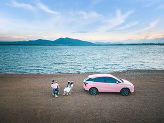 Fototapeta na wymiar Journey in holiday summer have pink car and young couples, tourists, travel on vacation. Relaxing and happy time. Destination at Huai Mai Teng Dam, Ratchaburi, Thailand, There is beautiful scenery.