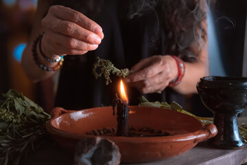 woman doing traditional ritual with black candle sea salt pepper in clay plate with herbs and...