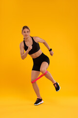 Fototapeta na wymiar Woman exercising with elastic resistance band on orange background
