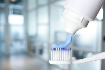 Squeezing toothpaste onto toothbrush against blurred background, space for text - obrazy, fototapety, plakaty