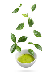Tasty green matcha tea in cup and leaves falling on white background