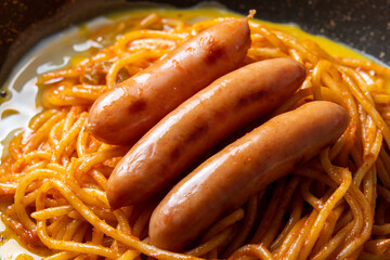 卵入りナポリタン(ウインナーソーセージのせ)をフライパンでつくる調理シーン。
