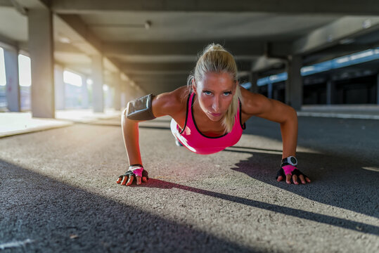 Beautiful sporty young woman doing push ups outdoors.