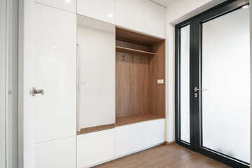 Modern entrance room of a family house with built-in wardrobes and a wardrobe wall made of white...