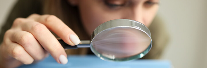 Woman looks at folders in drawer through magnifier glass