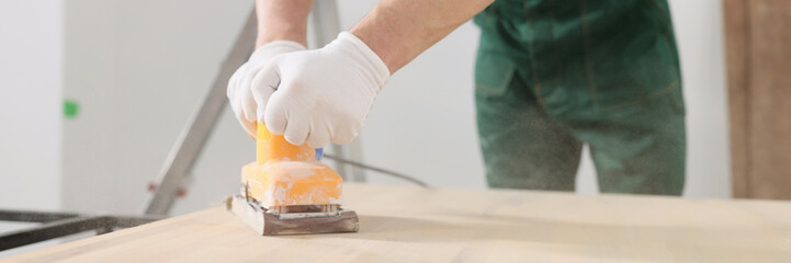 Skilled carpenter polishes wooden surface of office table