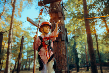 Little Girl Having Fun in a Rope Park Trail Facility. Happy little child enjoying climbing in an...