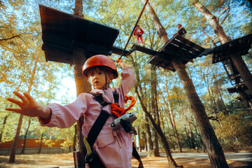 Little Girl Having Fun in a Rope Park Trail Facility. Happy little child enjoying climbing in an...