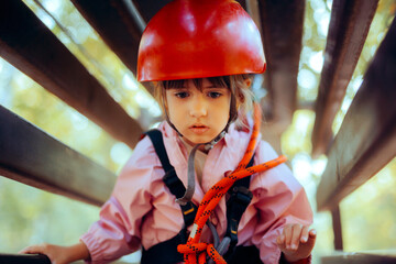 Little Girl Having Fun in a Rope Park Trail Facility. Happy little child enjoying climbing in an...