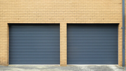 two grey colored corrugated metal garage doors against blonde brick wall