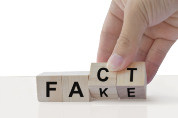 Hand flip wood cube change the word Fact or Fake isolated on transparent background. April fools day concept.