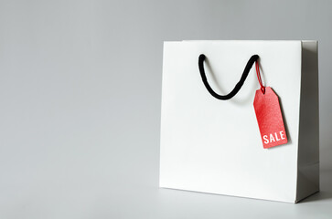 White shopping bag with word SALE at price tag on white background for Black Friday shopping sale concept.