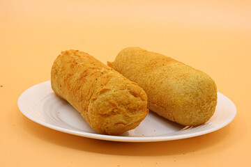 Brazilian fried snacks on a white plate over orange background