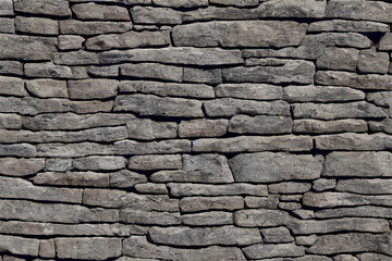 The surface of a wall composed of textured stone wall, creating a rustic and visually appealing...